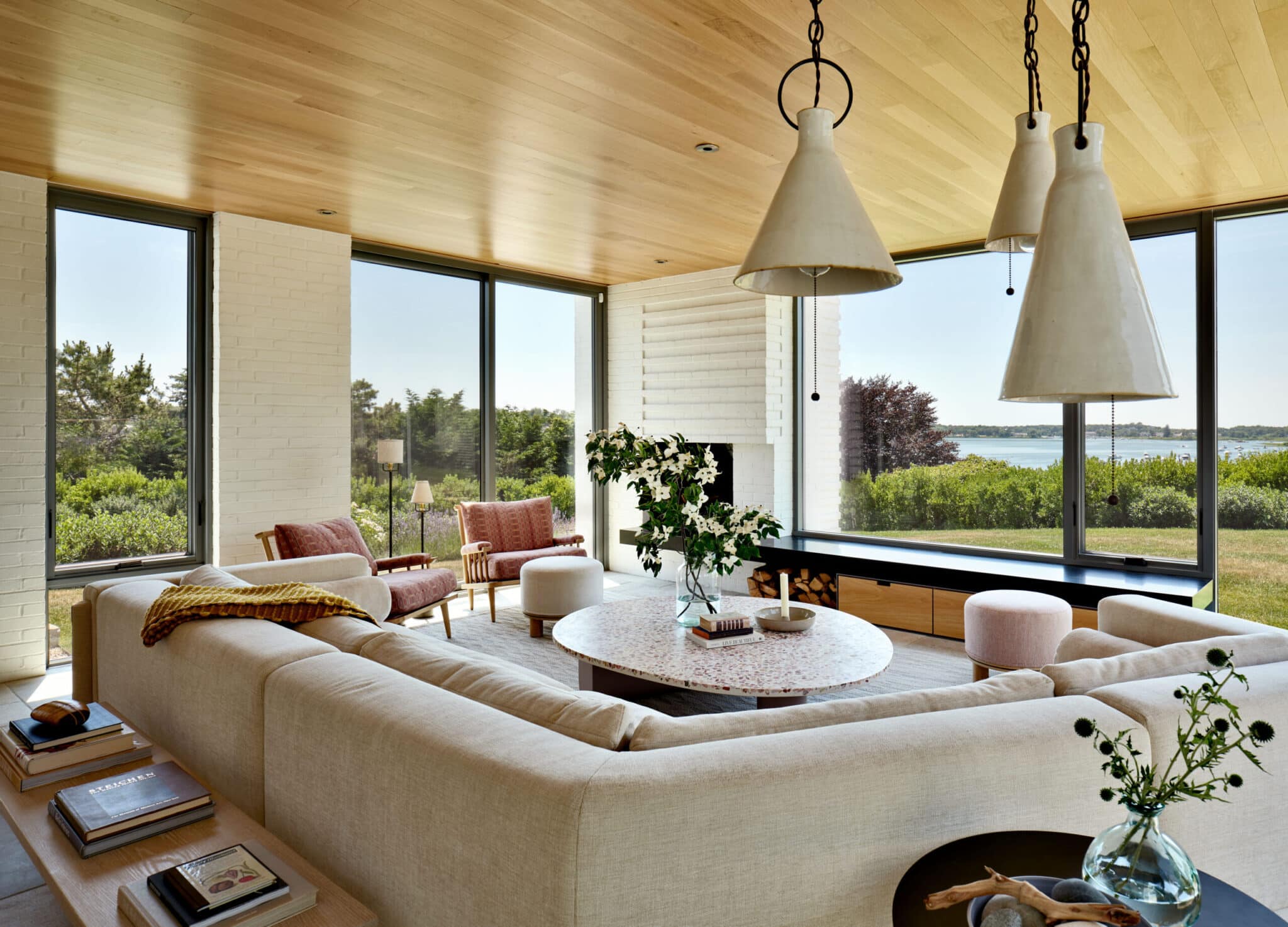 A large contemporary styled living room overlooking a grand lawn and pond in the distance.